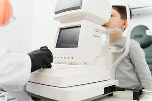 Optometry concept. Female optometrist optician doctor examines eyesight of child boy in eye ophthalmological clinic. photo