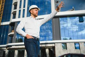 Engineer next to building cranes. Concept - large construction project. Architect directs the construction process. Drawings and tablet in the hands. photo