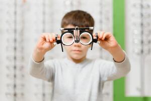 child boy showing trial frame in ophthalmology clinic, selective focus. photo