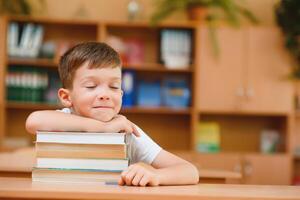 education and school concept - smiling little boy with many books at school photo