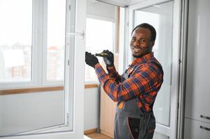 Workman in overalls installing or adjusting plastic windows in the living room at home photo