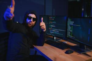 hacker sentado a escritorio en oscuro atmósfera. un computadora programador o hacker anónimo computadora hacker foto