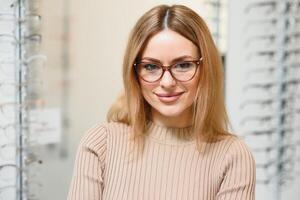 vista y visión concepto - joven negocio mujer elegir lentes a óptica almacenar. foto