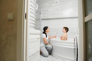 Mother washing little son in bathroom photo