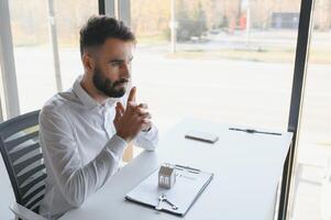 Portrait of a young realtor in the office at the table. Real estate sales concept. photo