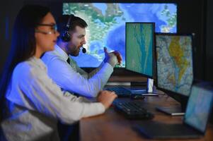 Center of dispatching maintenance. Portrait of cheerful woman and man working via headset microphone while sitting on navigation controller board photo