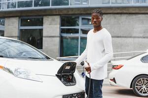 africano americano hombre cargando su eléctrico coche. foto