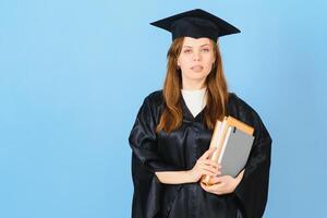 Woman graduate student wearing graduation hat and gown, on blue background photo