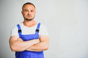 Portrait of young handyman standing on white background with copy space. Repairman wearing workwear uniform. photo