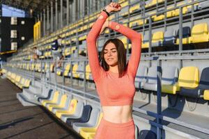 Sport and recreation concept. girl in sports wear posing at stadium before fitness exercise. photo