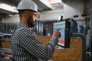 Portrait of Professional Heavy Industry Engineer Worker Wearing Safety Uniform, Hard Hat Smiling. In the Background Unfocused Large Industrial Factory. photo