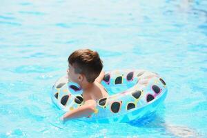 Happy Young Boy Floating in Swimming Pool on Raft photo