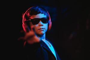 Studio shot in dark studio with neon light. Portrait of a stylish boy with headphones photo