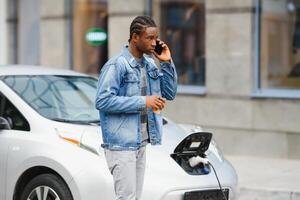 africano americano hombre cargando su eléctrico coche. foto
