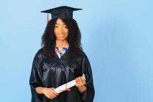 Young African-American student in bachelor robe on color background photo