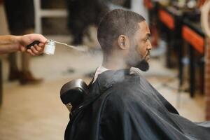 Black man in the barbershop. Cute black man makes a haircut in the African salon. Hair style. Haircut for adults. photo