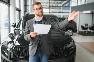 Good looking, cheerful and friendly salesman poses in a car salon or showroom. photo