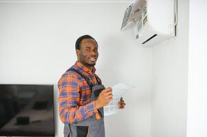 African American electrician repairing air conditioner indoors photo