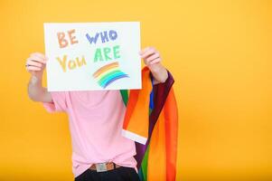 Hands of gay man holding lgbt banner on rainbow flag background lgbt symbol photo