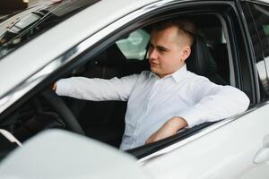 Portrait of an handsome smiling business man driving his car. photo