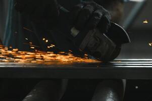 irreconocible metal trabajador molienda metal con un eléctrico sierra. foto