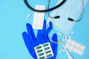 Scattered white pills on blue table.Medical, pharmacy and healthcare concept. Blue background white pills with a medical statoscope, top view photo