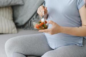 Beautiful healthy pregnant woman eating vegetable salad photo