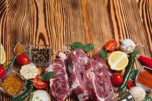 raw meat with fresh vegetables and spices on wooden background. Top view. Free space for text. prepare yourself concept. photo