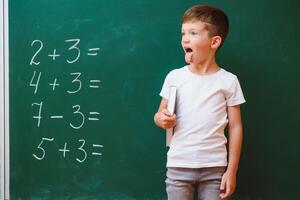 Funny schoolboy near the green school board in the classroom. Elementary school. Back to school. photo