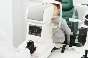 Optometry concept. Female optometrist optician doctor examines eyesight of child boy in eye ophthalmological clinic. photo