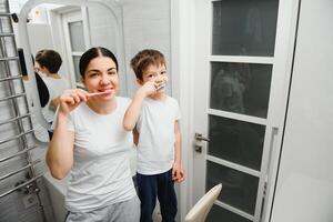 cute mother teaching kid boy teeth brushing photo