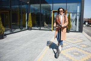 Young beautiful woman riding an electric scooter to work, modern girl, new generation, electric transport, ecology, ecological transport, sunset, electric skateboard. photo