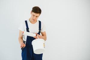 The painter is painting a wall in a room with a roller. photo