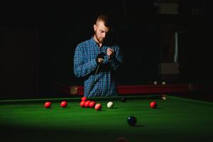 Young man playing billiards in the dark billiard club photo