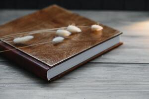 Family photo book with embossing. Photo book on a wooden background. Brown photo book with wood cover. Photoalbum with a hard cover. Wedding photo album.