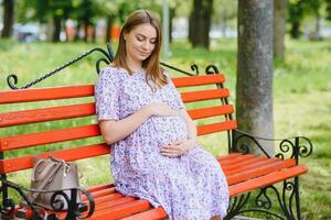 pregnant woman doing yoga in the park. sitting on the grass. photo