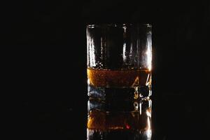 Whiskey glass black background shiny photo