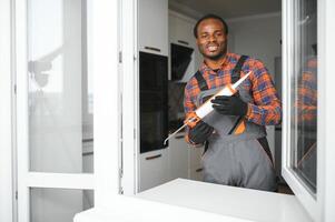 obrero en mono instalando o ajustando el plastico ventanas en el vivo habitación a hogar foto