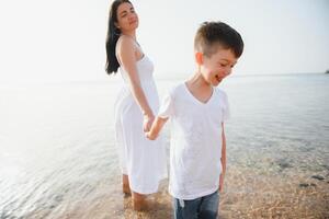 Mother and son playing on the beach at the day time. Concept of friendly family. photo