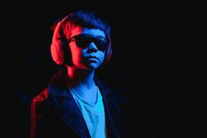 Studio shot in dark studio with neon light. Portrait of a stylish boy with headphones photo
