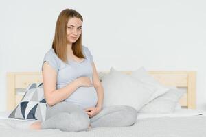 Young pregnant woman sitting on sofa photo