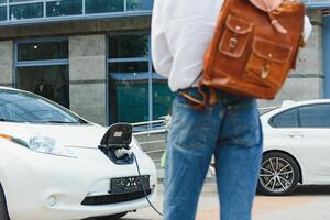 A handsome young man is charging his modern electric car. photo