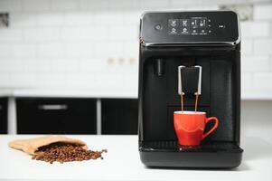 blurred background of kitchen and coffee machine with red cup and space for you photo