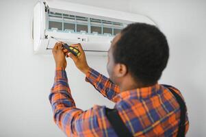 Young African Male Technician Repairing Air Conditioner photo