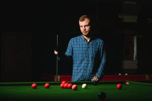 Young handsome man leaning over the table while playing snooker photo