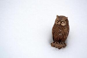 Owl statuette on the snow. Owl as a symbol of wisdom. photo