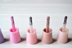 Palette of nail polish on the white wooden background with place for text. Manicure salon. photo