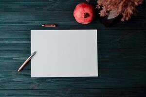 The sheet of white paper with pen and garnet on the dark blue wooden desk. Vintage background with place for text. photo