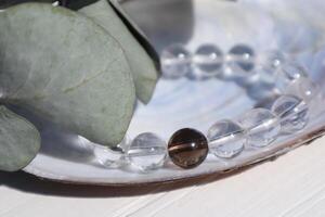 Bracelet made of rock-crystal and smoky quartz with decoration, close up. photo