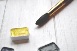 Tools for painting on the white wooden desk. Brushes and paints on the table. Painter's workplace. photo